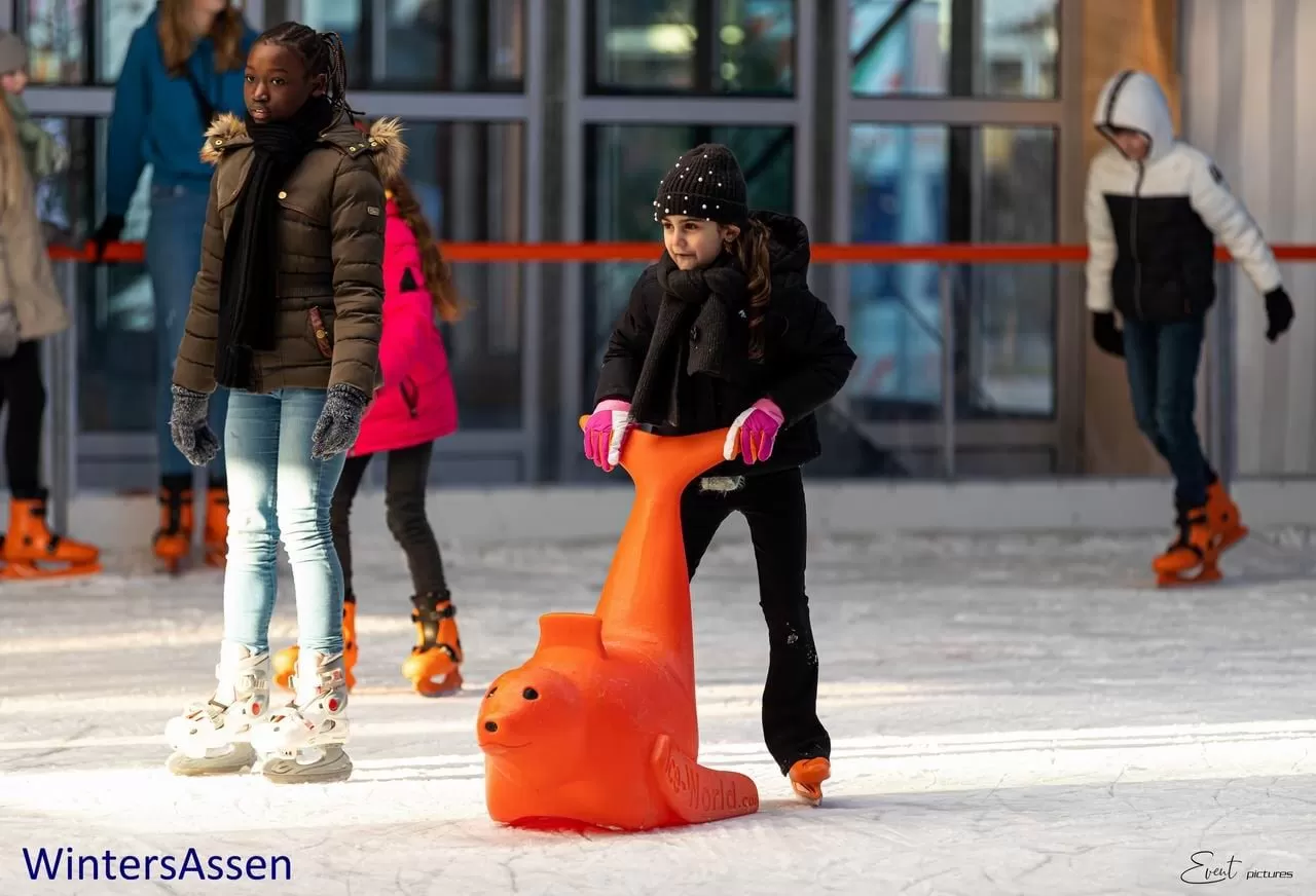 Kinderen schaatsen met een oranje zeehond als schaatshulp