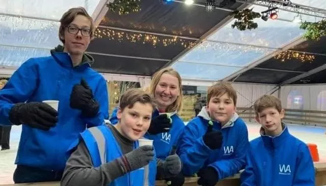 Vrijwilligers van WintersAssen in blauwe jassen op de ijsbaan